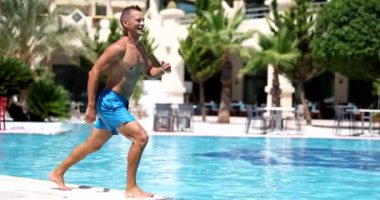 Havuza atlayan neşeli yakışıklı adam. Yaz tatilleri ve turistlerin olumlu duyguları