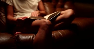 Kanepede kitap okuyan bir kadın. Yakın çekim 4K film ağır çekim. Hobi okuma konsepti 