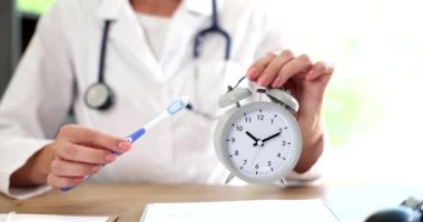 Klinikte çalışan doktor diş fırçası ve çalar saat tutuyor. Ağız temizliği.