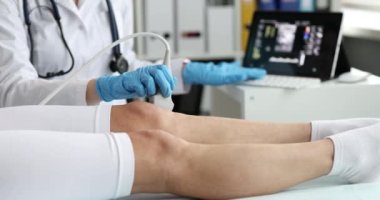 Doktor, klinikte ultrason cihazı kullanarak diz eklemlerini ultrasona sokuyor. Doktor hastanede kadın bacağına ultrason uygular.