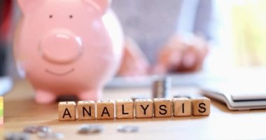 Muhasebeci masası mesaj analizinde domuzcuk bankasına yakın çekim. İş kadını klavyede hesap makinesi kullanıyor ve tasarrufları sayıyor