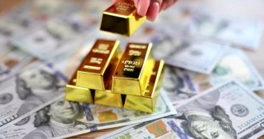 Kadın eli yığının üzerine altın külçeler ve dolar banknotları koyar. Kârlı yatırım faizi ve depoziti