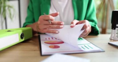 Ofiste elinde kalem olan bir kadın belgeleri karıştırıyor, yakın plan. Mali durumları kontrol etme kavramı