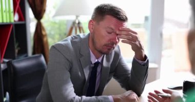 Ofisteki yorgun adam başını tutuyor, yakın plan. İş yerinde duygusal çöküntü kavramı, işten çıkarma.