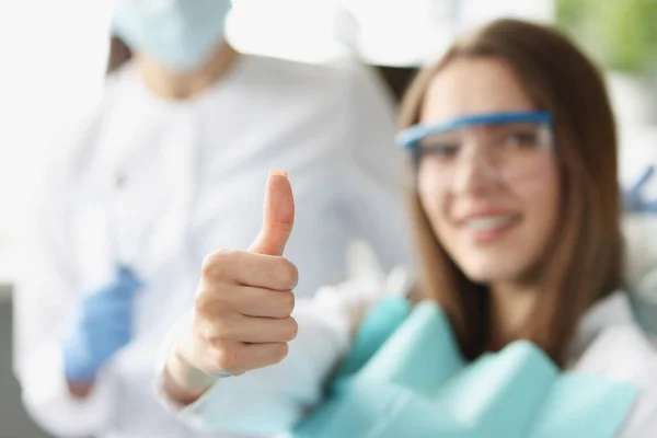牙医那里的一个女人露出了竖起大拇指的姿势 模糊的 近距离的 专业牙科护理 病人满意 — 图库照片