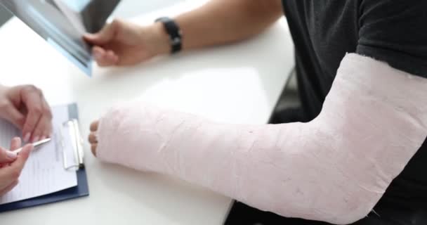 医生为胳膊上涂石膏的病人提供医疗咨询 手部骨折治疗概念 — 图库视频影像