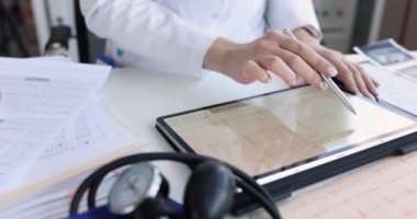 Kardiyolog tabletteki hastaya elektrokardiyogramı inceliyor. ECG 'nin normal ve patolojik konseptte deşifre edilmesi