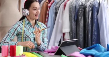 Atölyede elinde makas tutan neşeli kadın moda tasarımcısı. Kıyafet konsepti koleksiyonu oluşturmak için yaratıcı çalışma