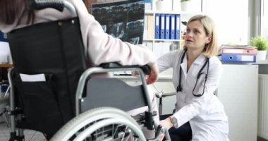 Ortopedik cerrah tekerlekli sandalyedeki hastanın diz mastürbasyonunu inceliyor. Omurga kavramının rehabilitasyonu ve travması