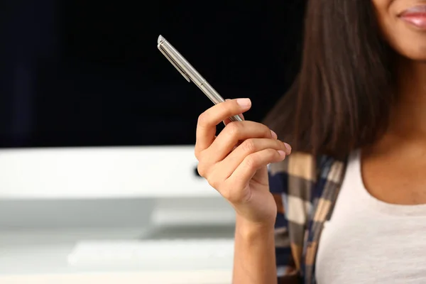 Woman hand holds metal pen on background of workplace. Gesture and sign training and education