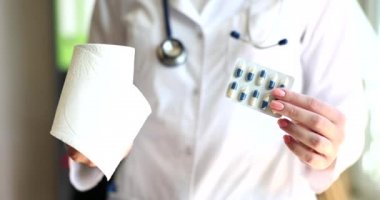 Doktor ishal için tuvalet kağıdı hapları tutuyor. Hazımsızlık ve hemoroit tedavisi