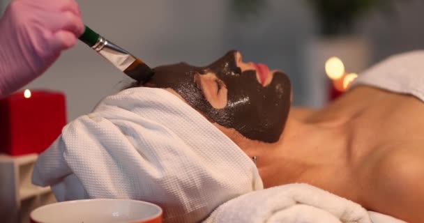 Cosmetoloog Zet Een Zwart Kleimasker Het Gezicht Van Een Mooie — Stockvideo