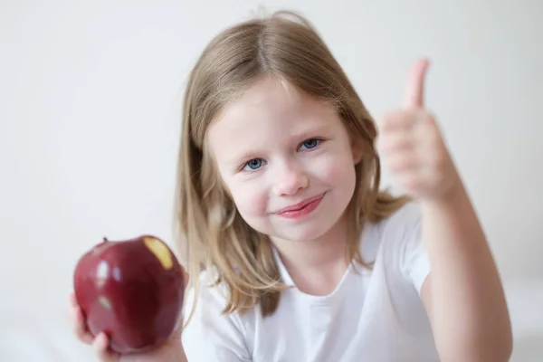 Söt Liten Flicka Håller Äpple Ena Handen Och Tummen Upp — Stockfoto
