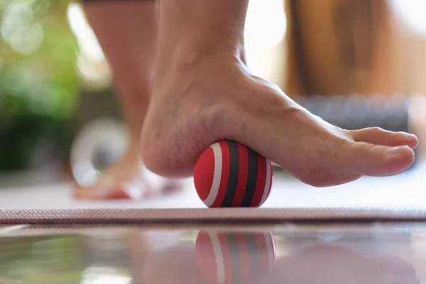 Person rolls ball on foot at home closeup. Foot massage ball concept