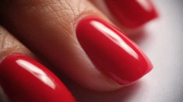Beautiful red silk manicure on female nails. Classic bright red manicure