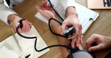 Kadın hemşire, tonometresi olan erkek hastaya yüksek tansiyon ölçer. Bakıcı kadın doktor hastanede erkek hastalarını düzenli olarak kontrol ediyor.