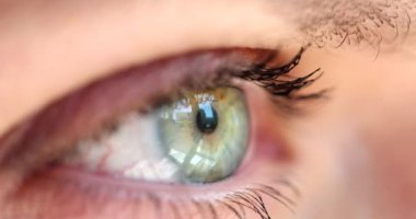 Genç ve güzel bir kadın, Iris 'in üzerinde mavi gri sarı gözleri açar. Maskaralar kirpiklere ve kırmızı kan damarlarına uygulanır.