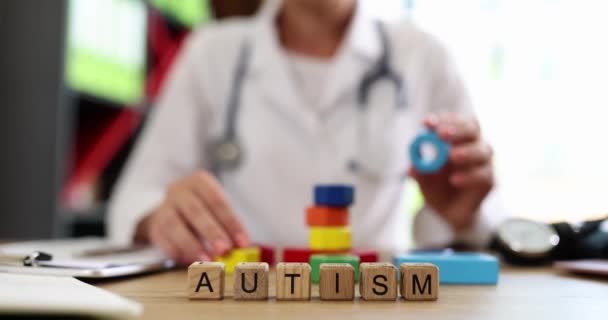 医師の手はカラフルなキューブとテキスト自閉症を収集します 自閉症スペクトラム障害と世界自閉症意識の日の概念 — ストック動画