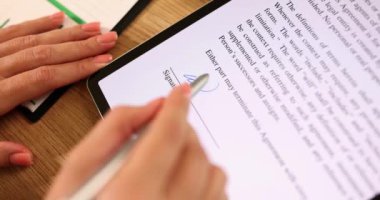 Tablet bilgisayarında kadın eli kalemle elektronik imza. Ofiste bilgisayarla ilgili anlaşma belgesini imzala..