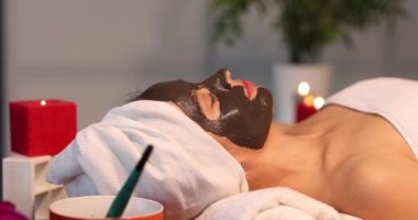 Kadın kaplıcaya kilden yüz maskesi takıyor ve cildine bakıyor. Yüz maskesi ve güzellik spa hizmetleri