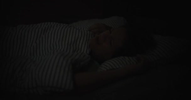躺在床上的年轻女子睁开了她的眼睛 失眠症闪烁着明亮的蓝光 夜梦和梦 — 图库视频影像