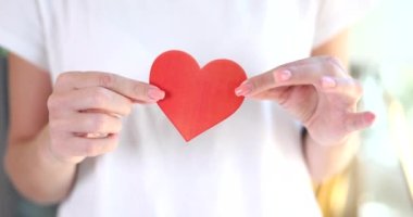 Kadın elleri göğsünde kırmızı kağıt kalp taşıyor. Romantik aşk sembolü ve yıldönümü ve sevgililer günü aşk konsepti.