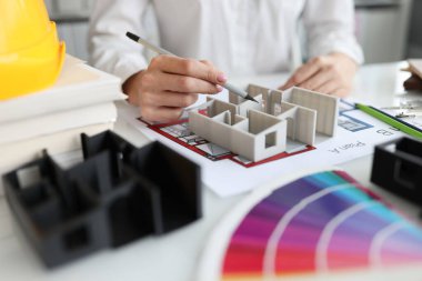 Stüdyoda 3 boyutlu ev modelini gösteren kadın tasarımcı. Daire yenileme konsepti için mimari planlar