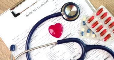 Kırmızı oyuncak kalpler ve tıbbi belgelerde bulunan haplarla steteskop 4K filmi yavaş çekimde çeker. Kardiyovasküler hastalıkların tedavisi 