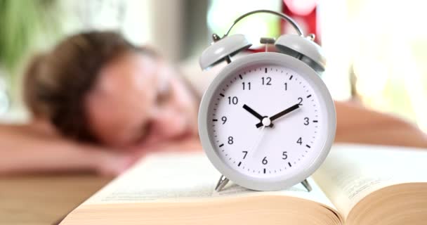 Reloj Despertador Gris Pie Libro Contra Fondo Mujer Dormida Primer — Vídeos de Stock