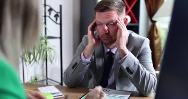 Ofiste, bir kadın yorgun bir adamla konuşuyor, yakın plan. İş yerinde duygusal stres, tükenme.