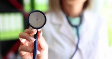 Steteskoplu kadın elinin yakın çekimi, yüzeysel odaklanma. Kardiyolog muayenesi, akciğer kontrolü.