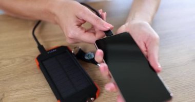 Kadınların elleri Powerbank 'ten akıllı telefonu şarj ediyor, yakın plan. Telefon şarjı, taşınabilir akamulatör