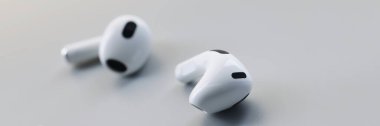 Gri arka planda beyaz kablosuz bluetooth kulaklıklar. Moda telefon aksesuarı, kulaklık sesi azaltma