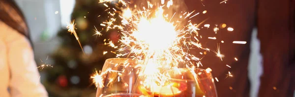 Close-up of people hands with fire sparklers and glass of champagne celebrate night and new start. Party, nightlife and new year eve. Joy, hope, christmas, new year concept