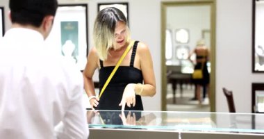 Genç bir kadın kendisi için güzel mücevherler seçiyor ve satıcıyla iletişim kuruyor. Gümüş ve altından yapılmış özel mücevherler.