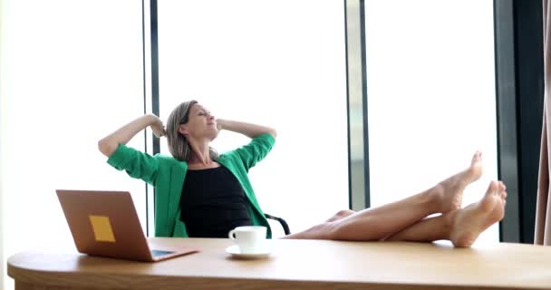 幸せな平和的な労働者の女性は快適なオフィスチェアにもたれる仕事の日の休憩中にヘッドリラックスの後ろに手を保持します 仕事の後の休息とリラクゼーションそして休暇についての夢を見て — ストック動画