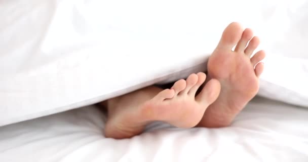 白い毛布の傷足の下の女性の足の閉鎖 そうだ 認識できない人は自宅でベッドで寝て休息とレジャーの概念 — ストック動画