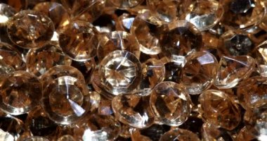 Kahverengi arka planda duran ve güneş ışığında parlayan elmaslar yığını. Elması işlemenin teknolojik süreci dahice.