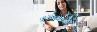 Oturma odasında gitar çalan güzel esmer kadının portresi, kadın müzik aletinde yeni bir hobi edinmek için boş zaman harcıyor. Müzik, hobi konsepti
