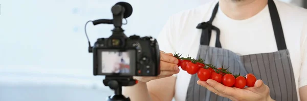 特写的Vlogger厨师显示成熟的西红柿成分 男人在围裙记录红色蔬菜相机烹饪Vlog 烹调概念 — 图库照片