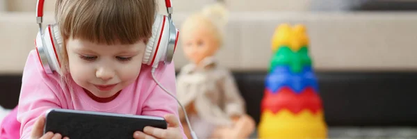 Low angle of little girl kid watching cartoon on smartphone device, digital entertainment for child. Funny pastime on holiday. Play, social media concept