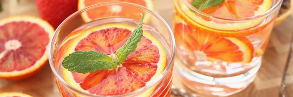 Close-up of cooling drinks cocktails in glasses, grapefruit with mint, cheers or toast. Summer fruit beverages for company. Party, harvest, vitamin concept