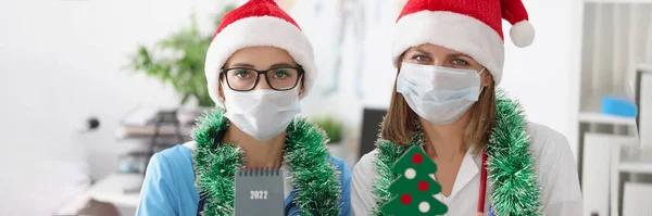 医療従事者の肖像画は 顔のマスク お祝いの帽子や装飾で新年を満たしています 受付の医師と看護師 パンデミック ウイルス拡散の概念を防ぐ — ストック写真