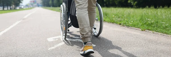 Low angle of man drive person in wheelchair, friend visit someone in nursing house. Go for walk in park, treatment for recovery. Disability, health concept