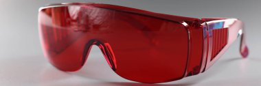 Kırmızı plastik güvenlik gözlüğü yakın plan, ustabaşı için koruyucu gözlük. Gri arka planda yeniden kullanılabilir gözlük. Mesleki güvenlik kavramı