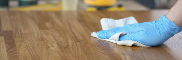 Close-up of carpenter male polish wooden plank with cloth, worker remove dust from wooden surface. Carpentry work, renovation, interior, builder concept