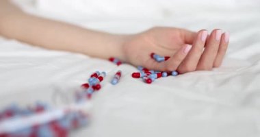 Kadın eli intihar haplarıyla yatağa uzanıyor. Aşırı doz veya intihar hapları