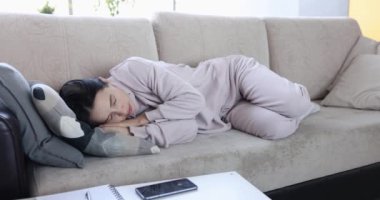 Kadın kanepede uyuyor ve telefonu kapatıyor. Uykusuzluk ve ilgisizlik konsepti