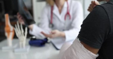 Doktor kırık kollu hastanın röntgenini inceliyor. Klinik konseptinde travmatolog danışmanlığı