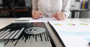 Elinde kalem tutan kadın özet raporuna ve hesaplı finansmana işaret ediyor. Pazarlama istatistikleri ve analitik kavramı